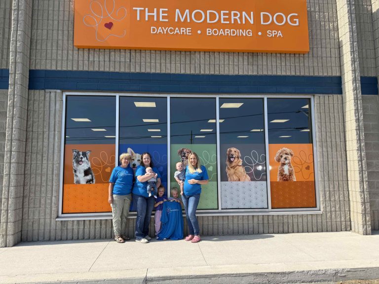 Three female business owners standing with their young children in front of their dog daycare